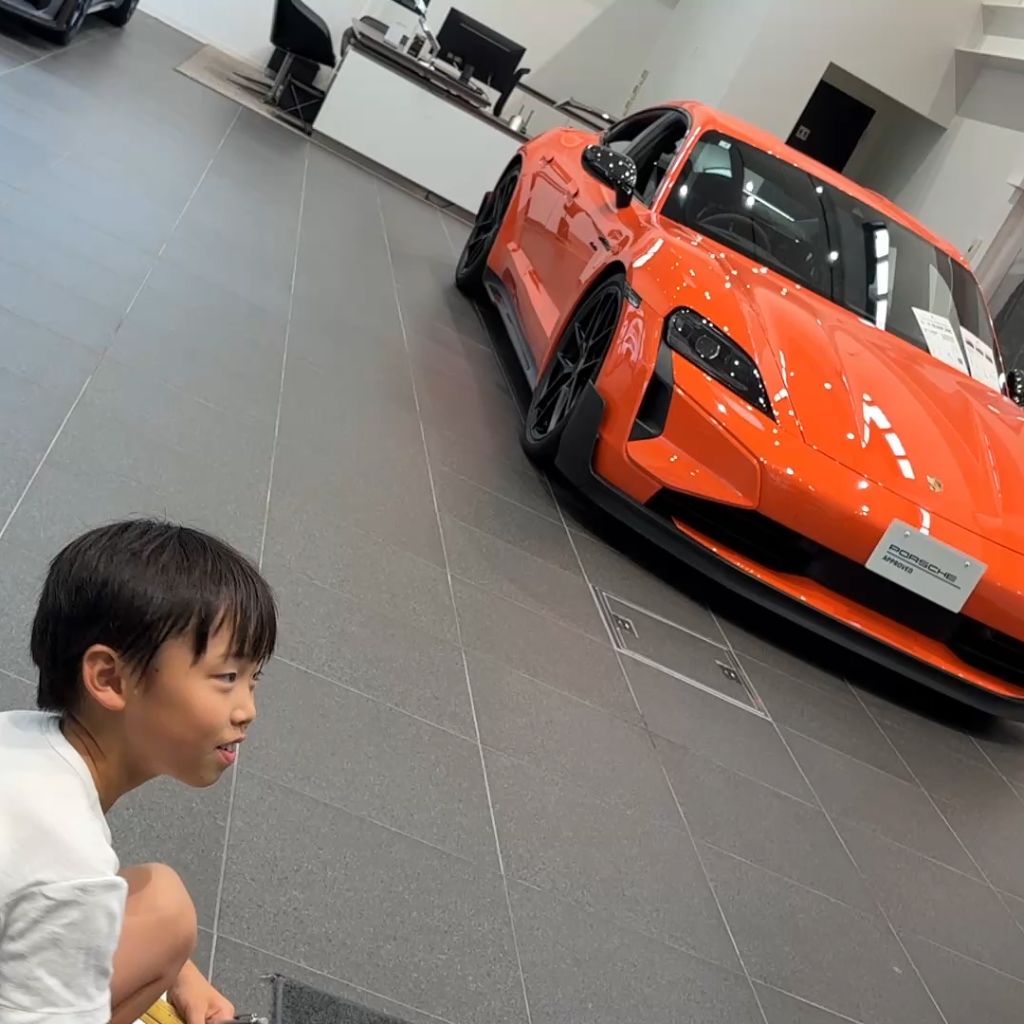 YugenK gazing at an orange Porsche Taycan in the showroom